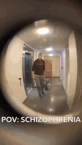 a man is walking down a hallway with a bag in his hand and a peephole .