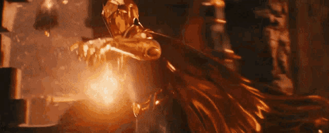 a woman in a gold cape is standing in a dark room holding a sword