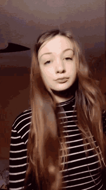 a woman wearing a black and white striped shirt looks at the camera