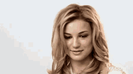 a close up of a woman 's face with long blonde hair and a white shirt .