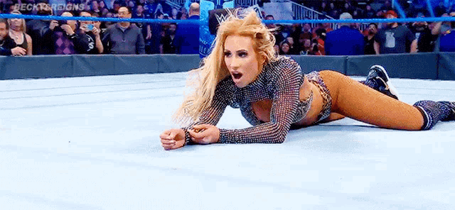 a female wrestler is laying on the ground in a wrestling ring .