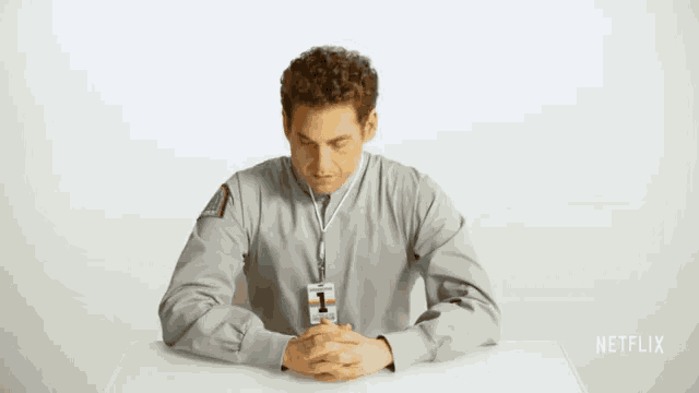 a man sitting at a table with a lanyard around his neck that says netflix on it