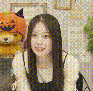 a woman wearing a pumpkin hat is smiling in front of a teddy bear