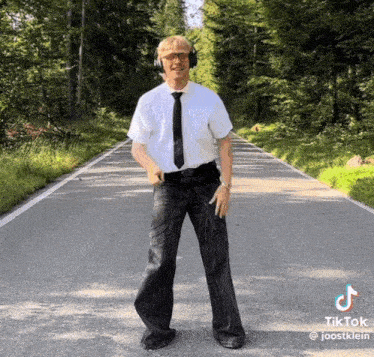 a man wearing headphones and a tie is standing in the middle of a road ..