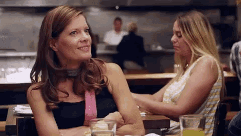 two women are sitting at a table in a restaurant talking