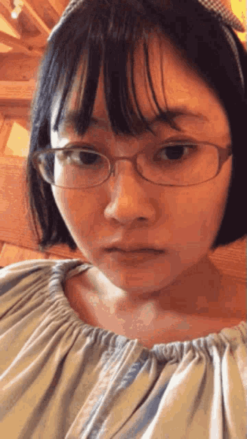 a girl wearing glasses and a headband is making a face