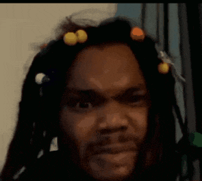 a man with dreadlocks and a beard is making a funny face