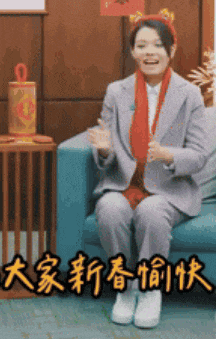 a woman in a suit and scarf is sitting on a couch