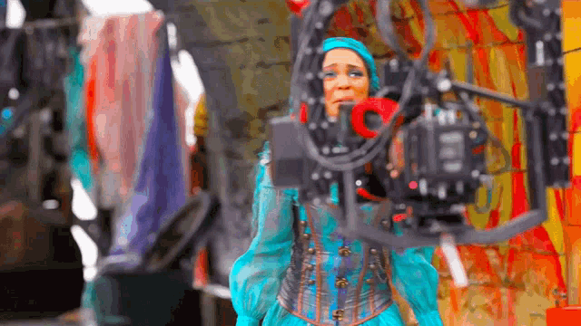 a woman in a blue costume is standing in front of a camera