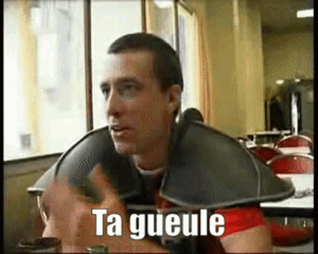 a man sitting at a table with the word ta gueule on the screen