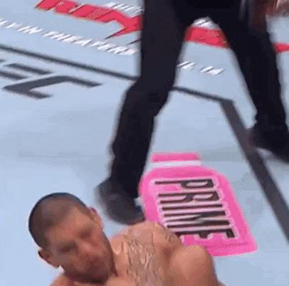 a man is laying on the ground while a referee stands behind him .