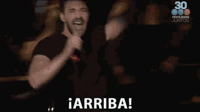 a man is singing into a microphone and the words arriba are visible