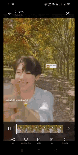 a phone screen shows a video of a man in a park with trees in the background .