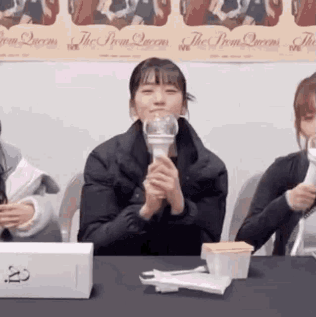 a woman is sitting at a table holding a light stick and smiling .