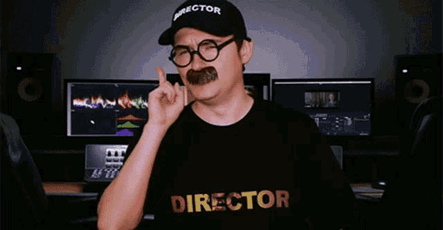 a man with a mustache and glasses is wearing a black shirt that says director