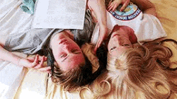 three people are laying on a bed with their heads together .