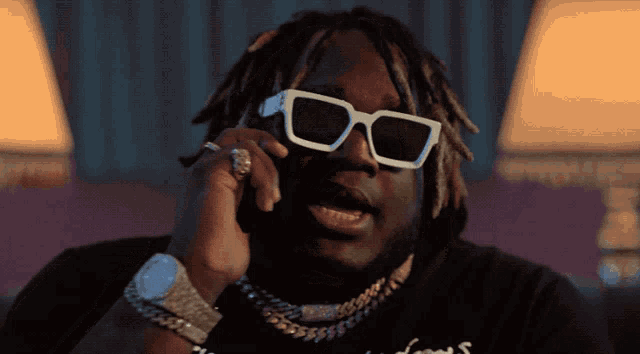 a man wearing sunglasses and a watch talking on a cell phone