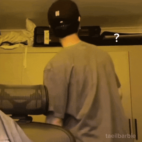 a man wearing a hat and a grey shirt with a question mark on his back