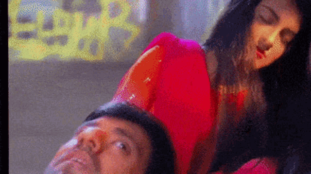 a woman in a red saree is laying on a man 's back .