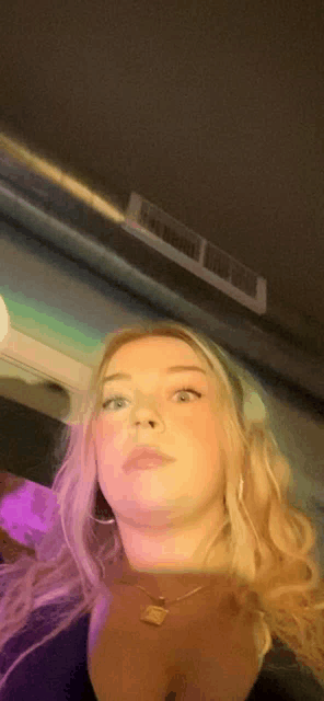 a woman is taking a selfie in a dark room with purple lights behind her .