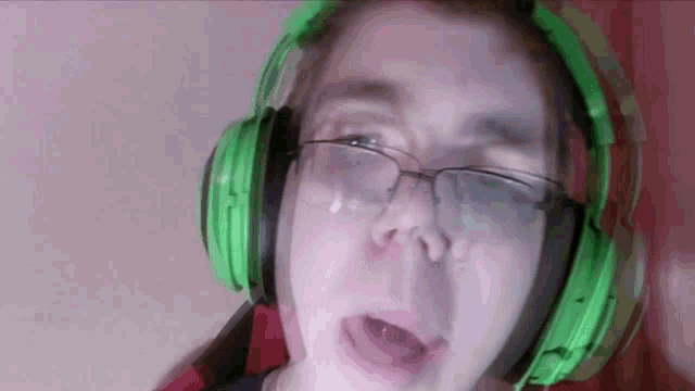 a man wearing green headphones and glasses is crying .