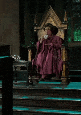 a woman in a purple robe sits on a throne holding a cup