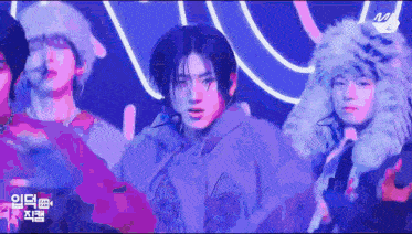 a group of young men are standing on a stage wearing fur hats and jackets .