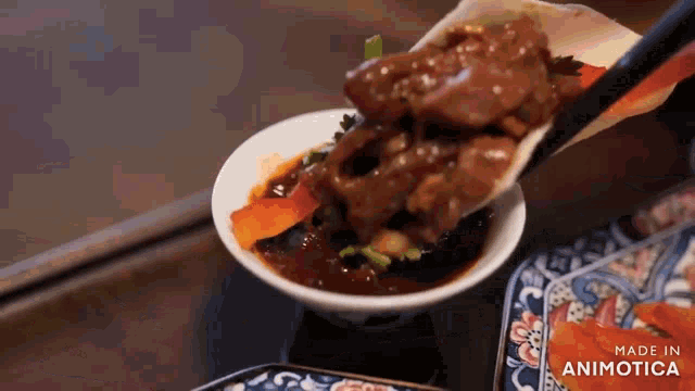 a person is dipping a piece of meat in a sauce .