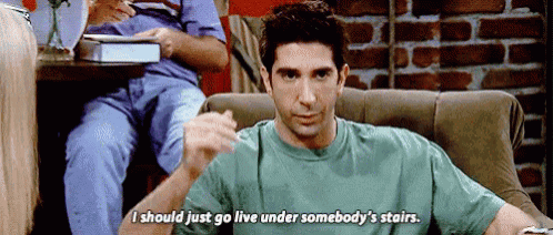a man in a green shirt is sitting on a couch and saying i should just go live under somebody 's stairs