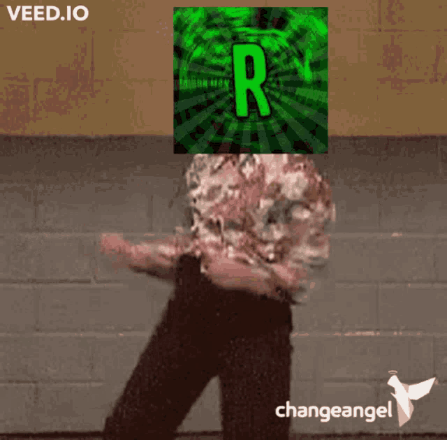 a man is dancing in front of a wall with a green r on his head