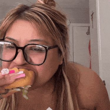 a woman wearing glasses is eating a donut