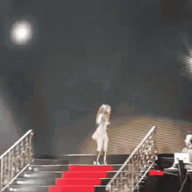 a woman is walking down a red carpeted staircase .