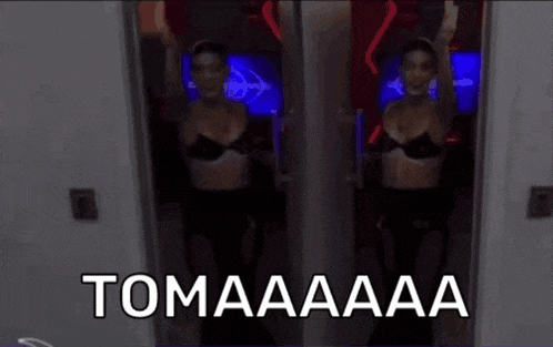 a woman in a bra stands in front of a painting that says " tomaaaa "