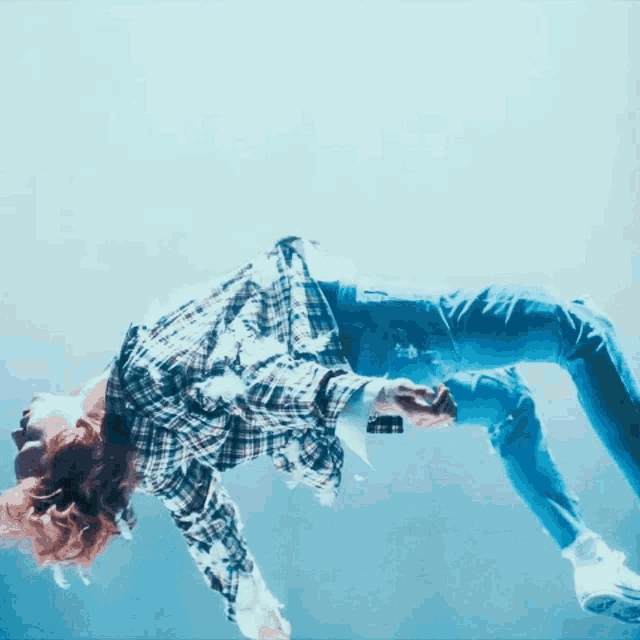 a person in a plaid shirt and jeans is floating in the air
