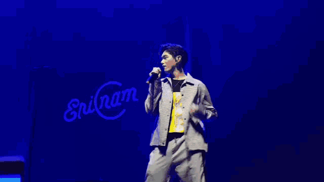 a man in a suit is dancing on a stage while holding a microphone .