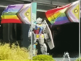 a robot with a shield stands in front of a rainbow flag