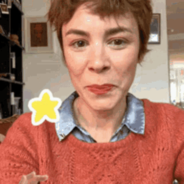 a woman wearing a red sweater has a yellow star on her neck