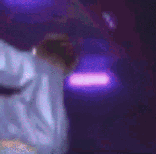a close up of a person 's face with a purple light behind them