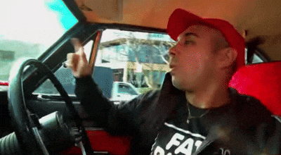 a man in a red hat is smoking a cigarette while sitting in a car