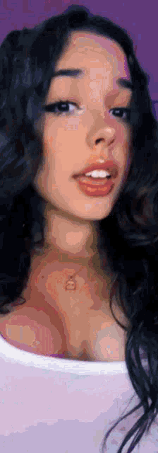 a close up of a woman 's face with a purple background and a white shirt on .