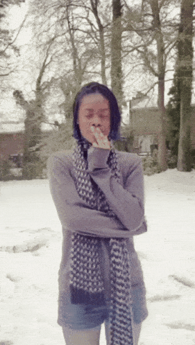 a woman wearing a scarf and a sweater covering her mouth with her hands