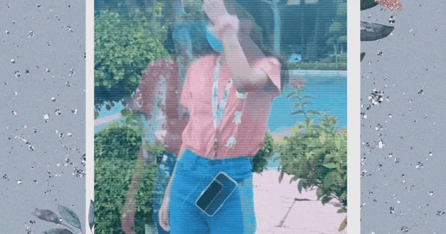 a girl in a pink shirt and blue shorts holds a cell phone