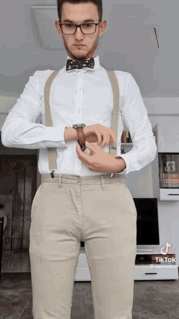 a man wearing a bow tie and suspenders looks at his watch