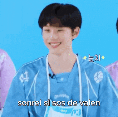 a young man wearing an apron and a blue shirt is smiling and says sonrei si sos de valen .