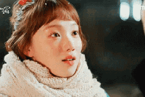 a close up of a woman 's face wearing a scarf and a flower in her hair .