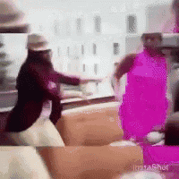 a woman in a pink dress is standing next to a man in a red jacket on a couch .