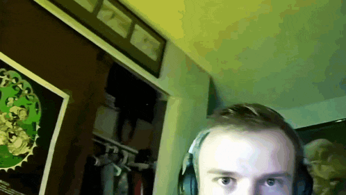 a man wearing headphones looks at the camera in a room with a poster on the wall that says ' apocalypse '