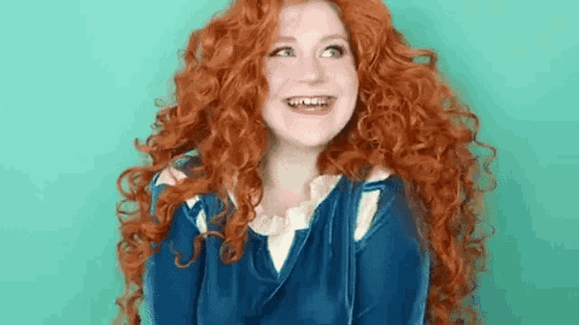 a woman with red curly hair is wearing a blue dress and a blue jacket .
