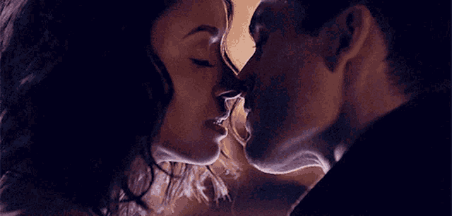 a man and woman are kissing in a dark room