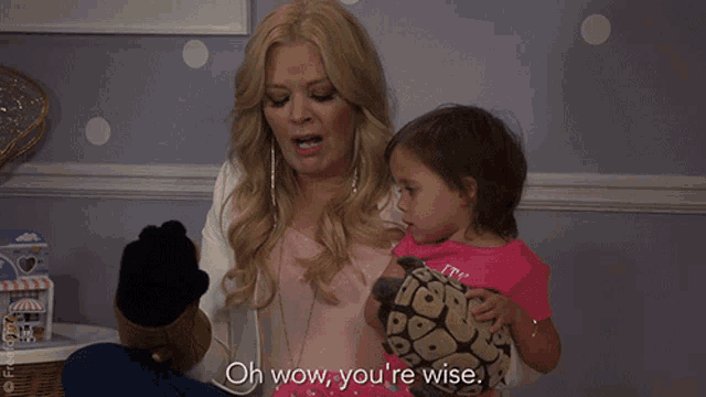 a woman is holding a little girl and says " oh wow you 're wise "
